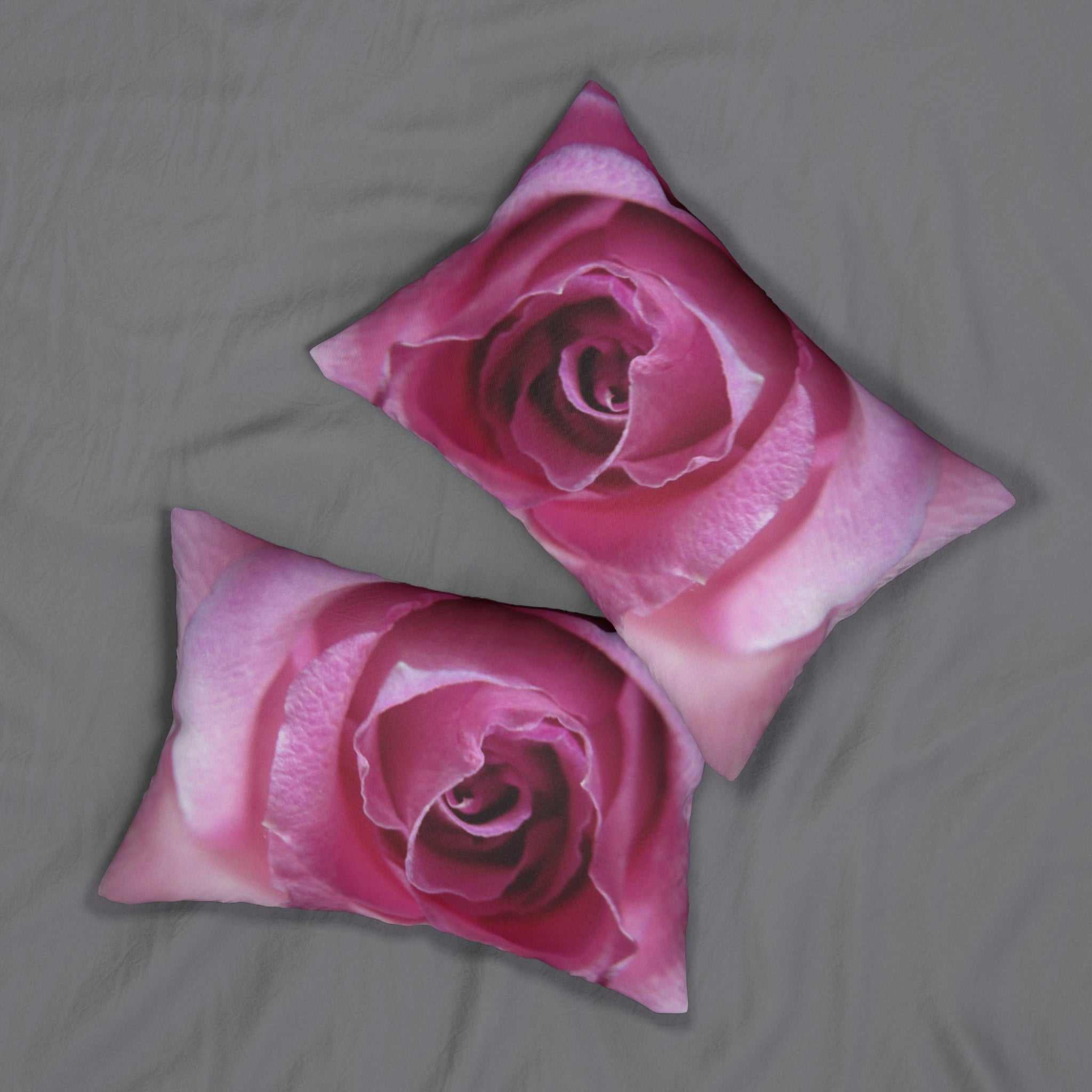 Two pink rose-patterned pillows on a gray surface