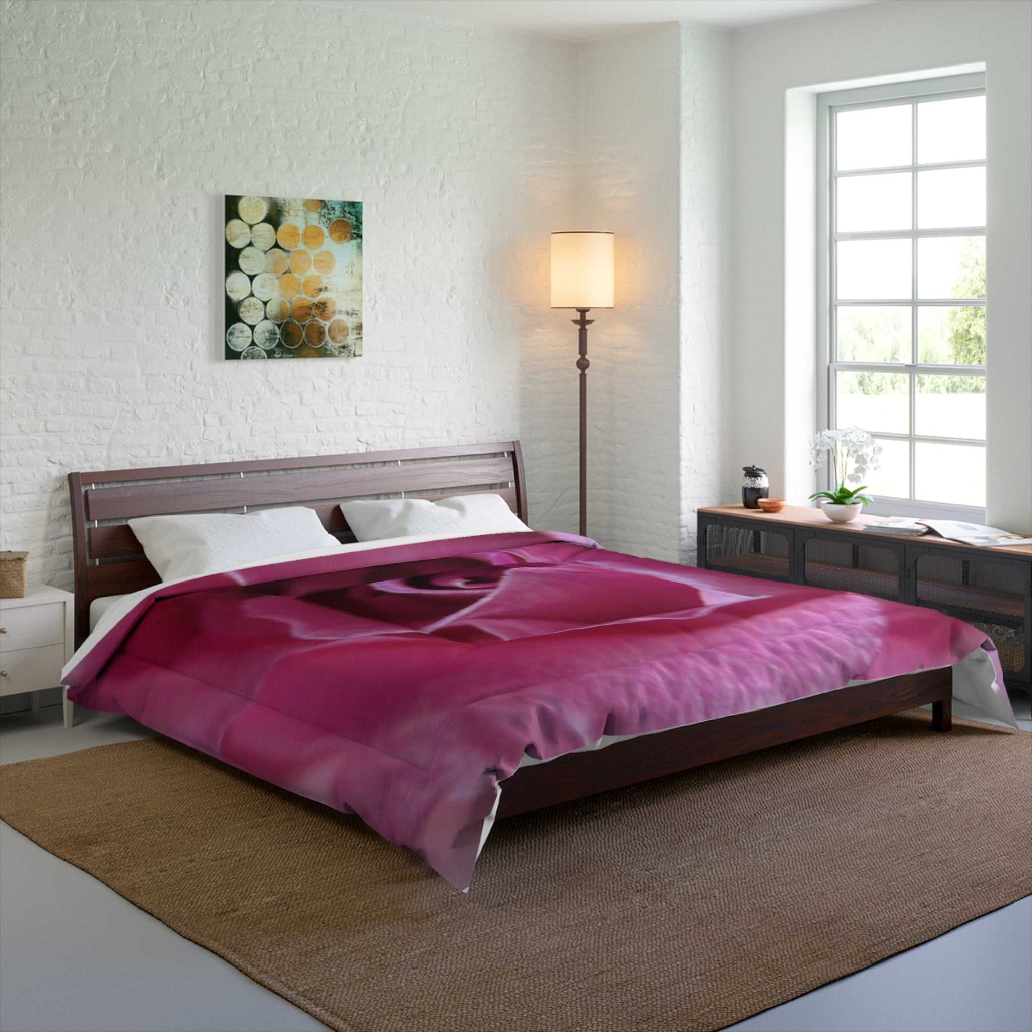Bedroom with a pink rose comforter on a bed, lamp, and artwork on the wall.