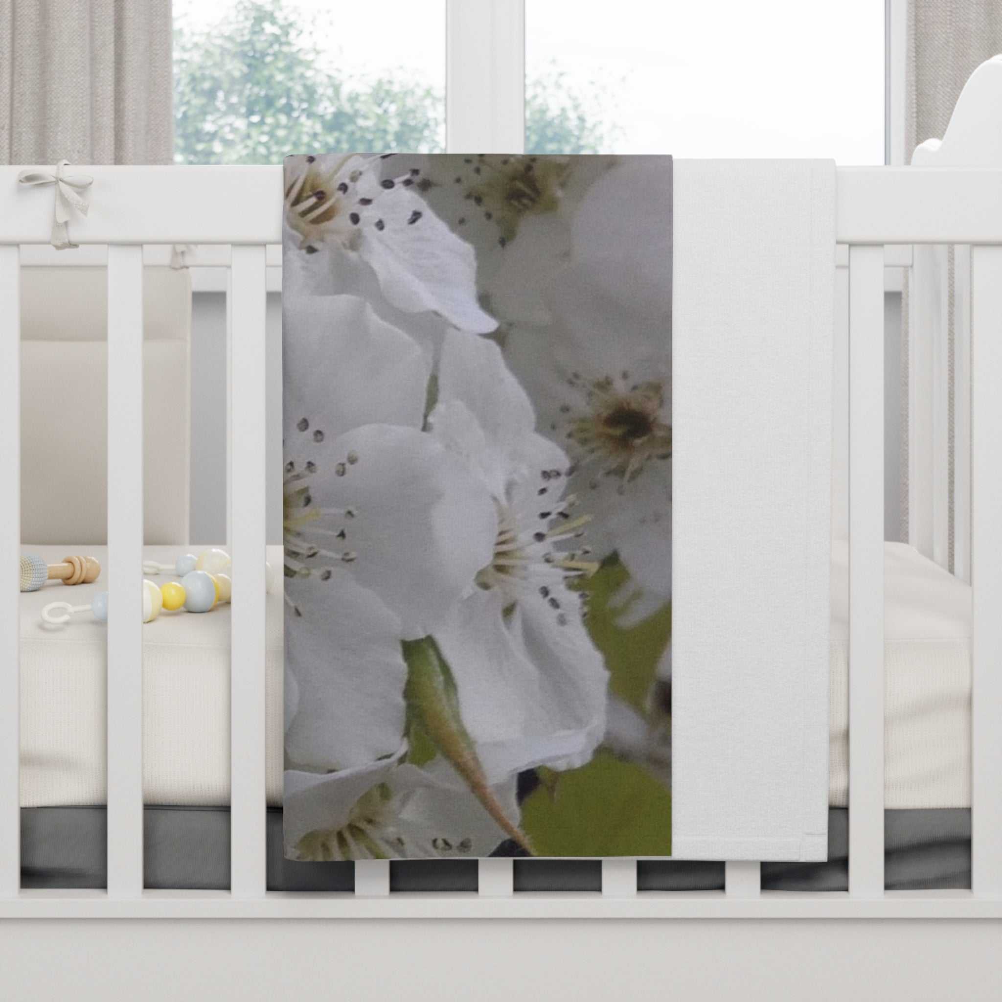 White floral soft fleece baby blanket draped over crib railing, gentle and cozy for nursery use