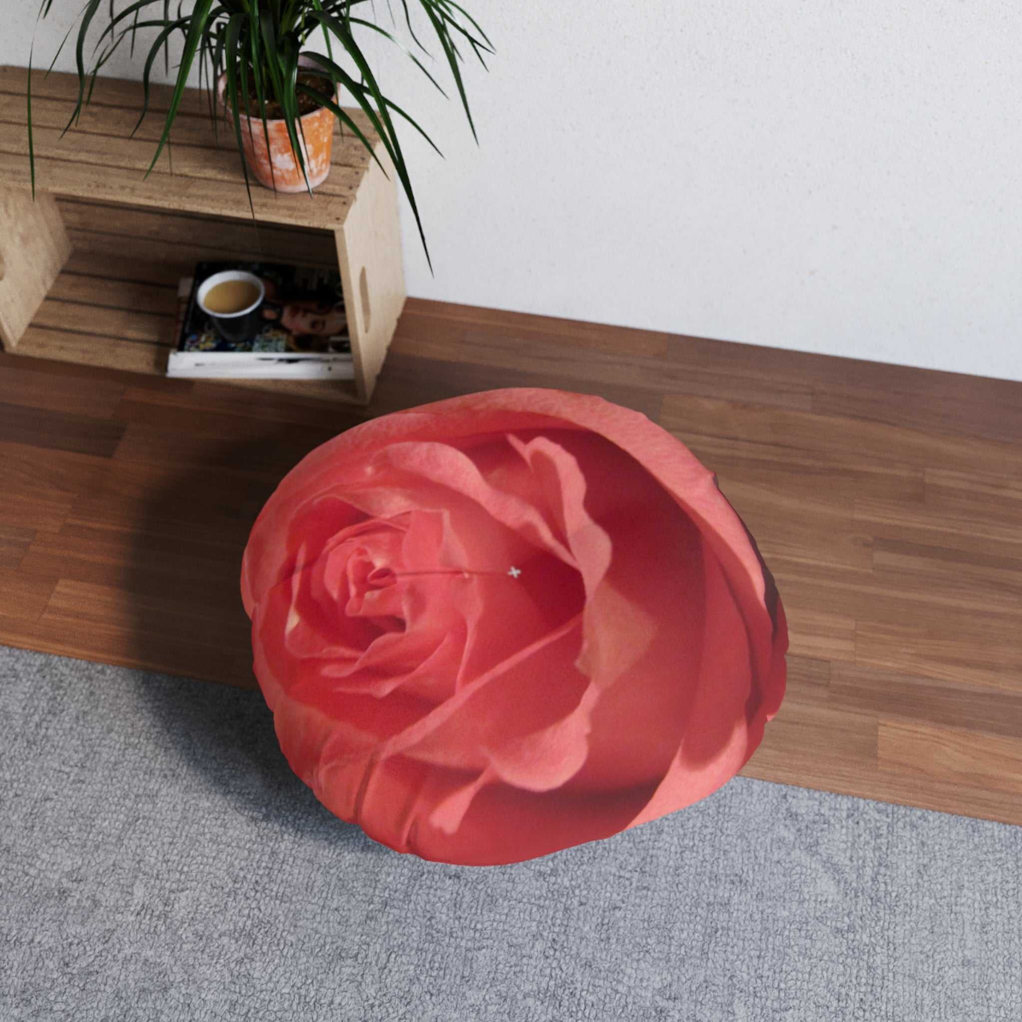 Red rose-shaped ottoman on a wooden floor with a plant and small table in the background.